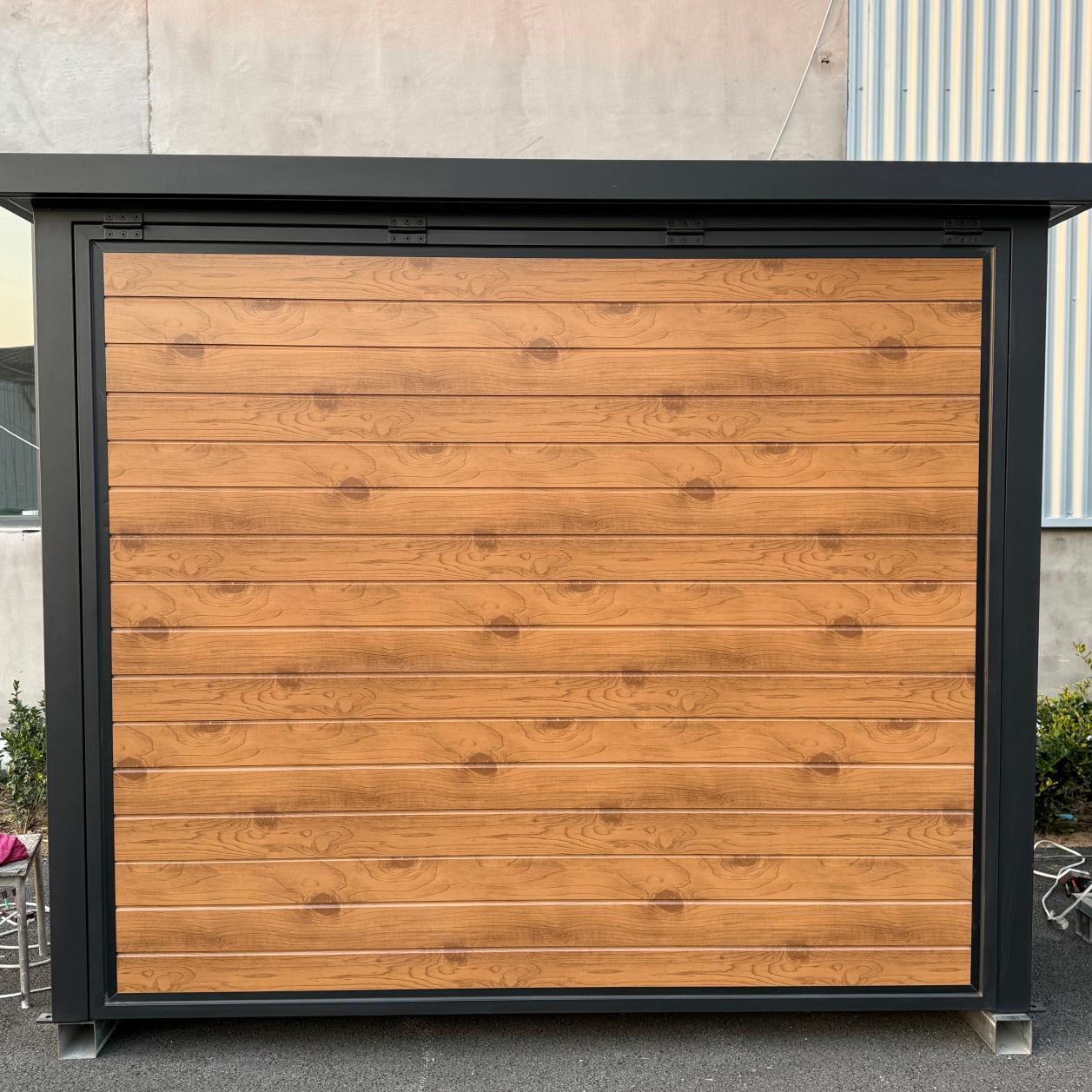 Closed outdoor kitchen pod with black frame and timber-look exterior